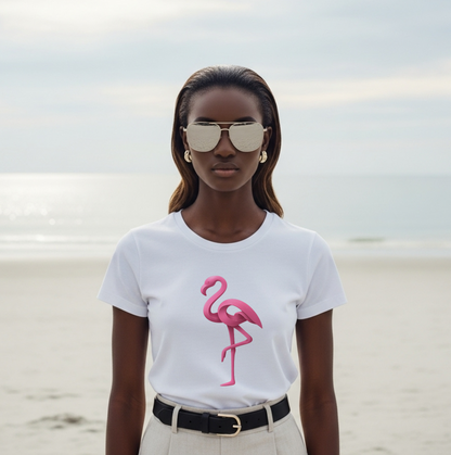 Woman wearing a white t-shirt with a pink flamingo design on a beach.