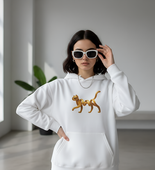 Person wearing a white hoodie with a golden cat design, standing indoors.