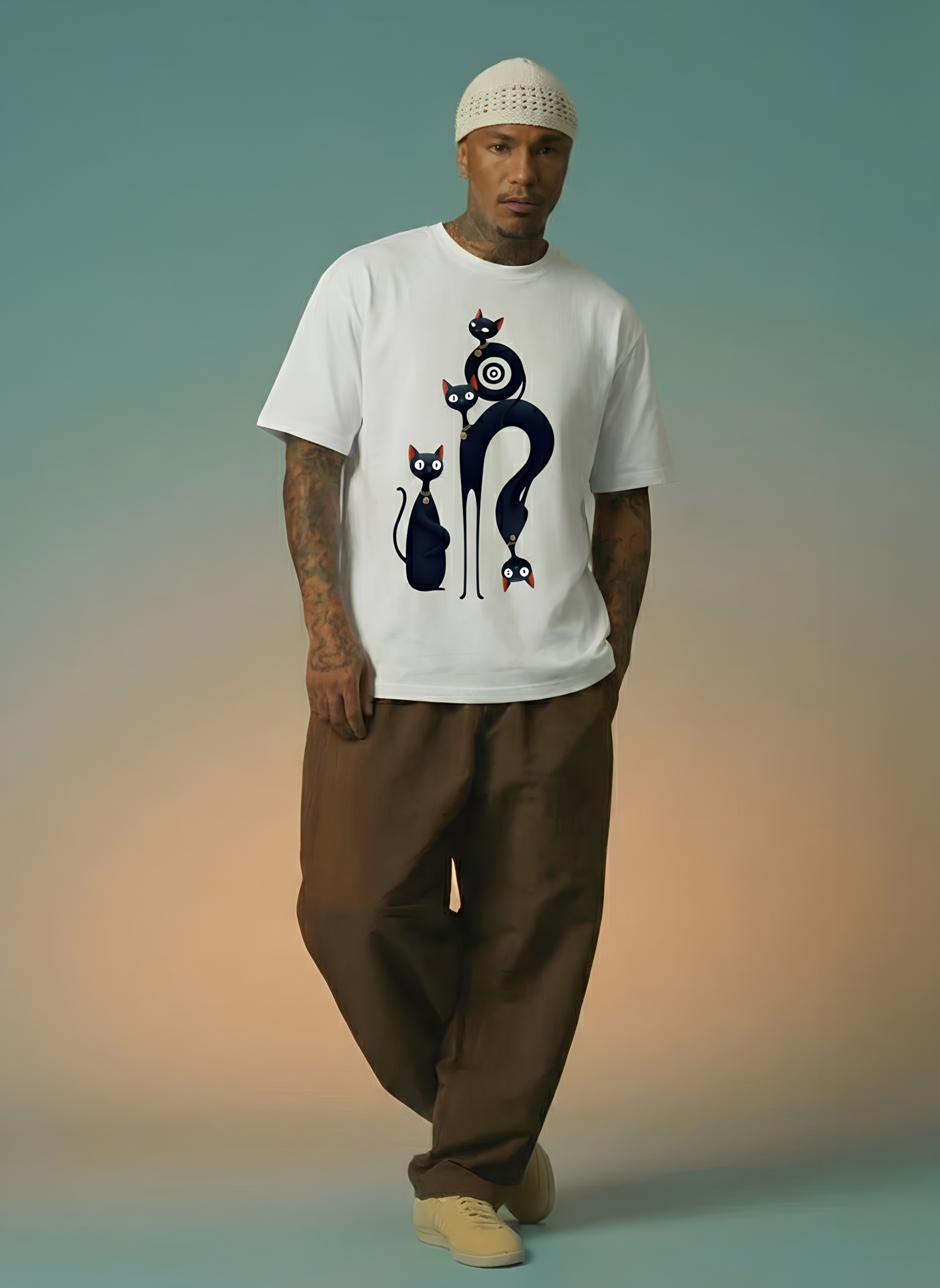 Man wearing a white t-shirt with a graphic design of playful black cats, standing against a gradient background.