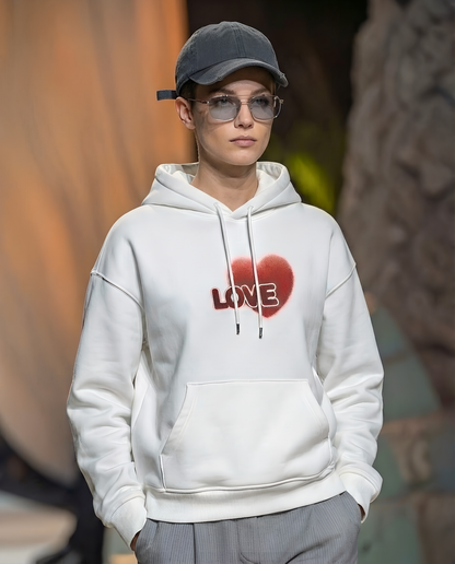 Person wearing a white hoodie with a red heart and 'LOVE' text, gray cap, and sunglasses.