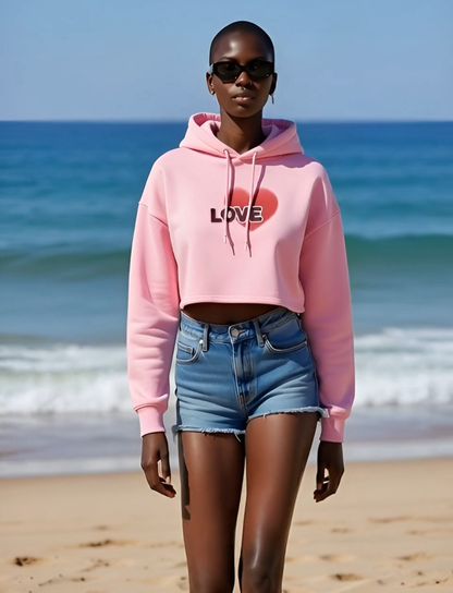 Person wearing a pink hoodie with 'LOVE' and a heart design on a beach.