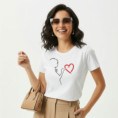 Woman wearing a white t-shirt with a graphic design (painting love), holding a beige handbag on a light gray background
