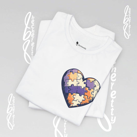 White t-shirt with a colorful heart-shaped puzzle design, on the top left corner.