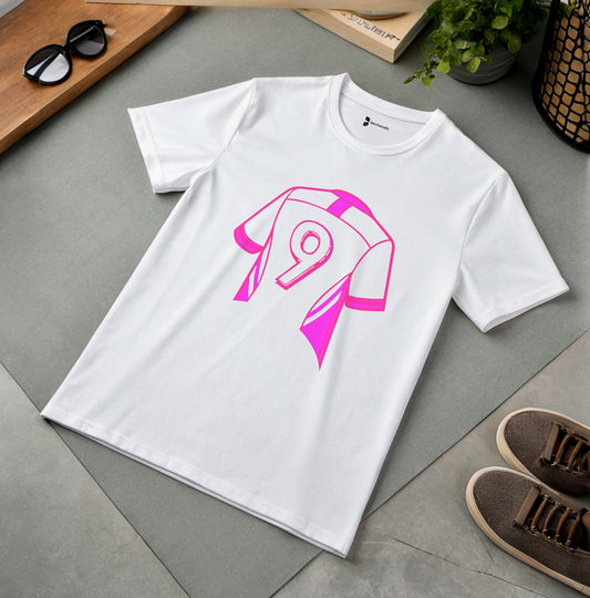 White t-shirt with pink graphic Number 9, design on a gray surface with shoes and plant in the background